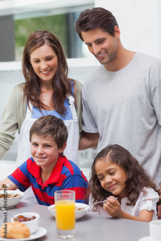 Parents looking at their children having breakfast