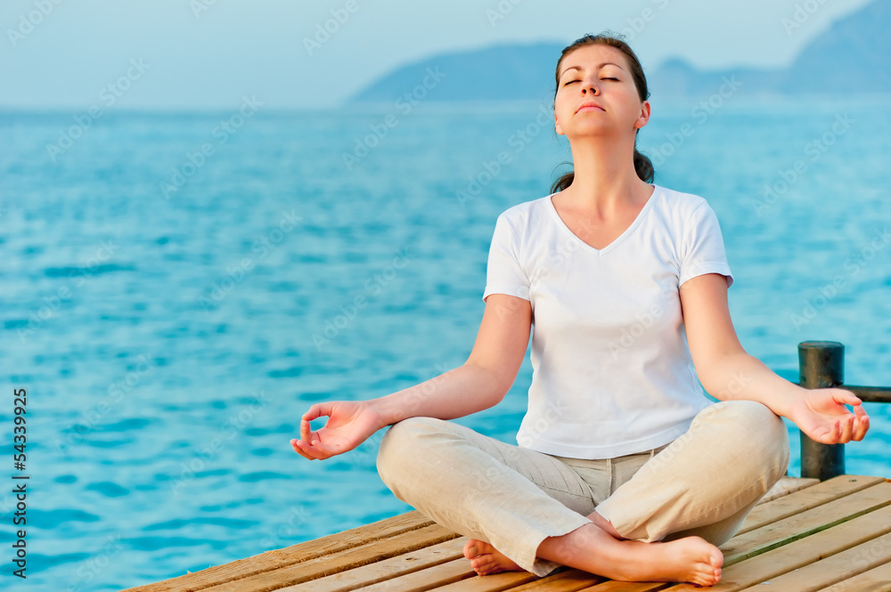 girl sitting on a pier in the lotus position