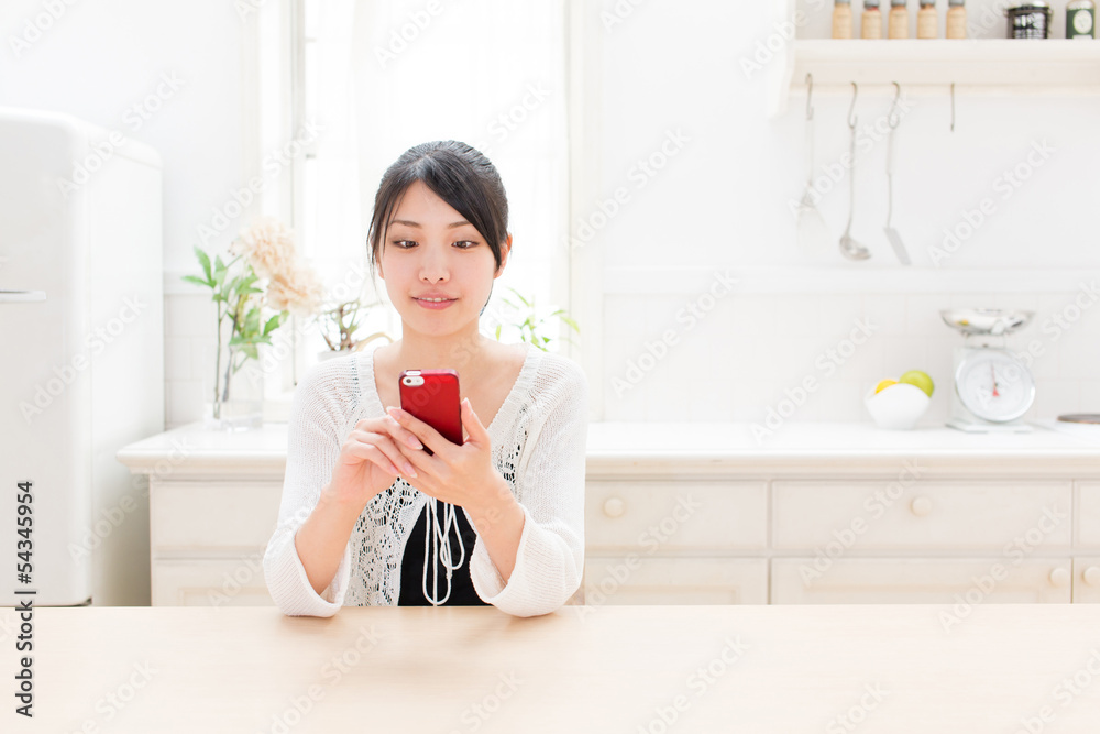 young asian woman using smart phone in the kitchen young asian woman using smart phone in the kitchen