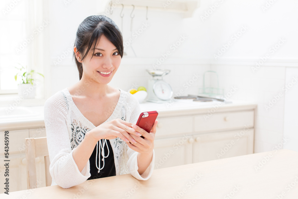 young asian woman using smart phone in the kitchen young asian woman using smart phone in the kitchen