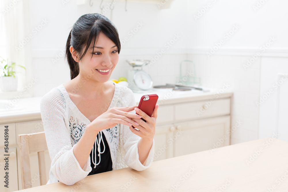 young asian woman using smart phone in the kitchen young asian woman using smart phone in the kitchen