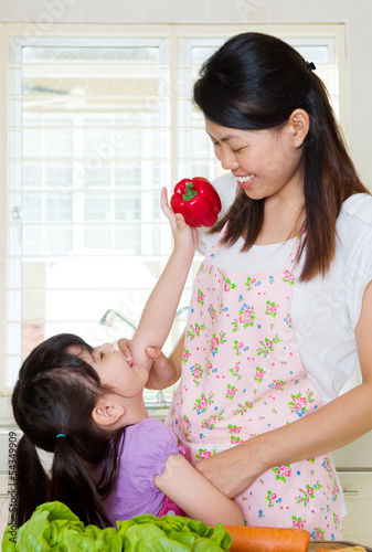 Little asian girl helping mom in the kitchen