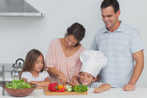 Children looking at their mother who is cutting vegetables