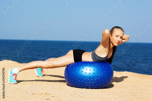 Young happy woman doing fitness exercises on the ball