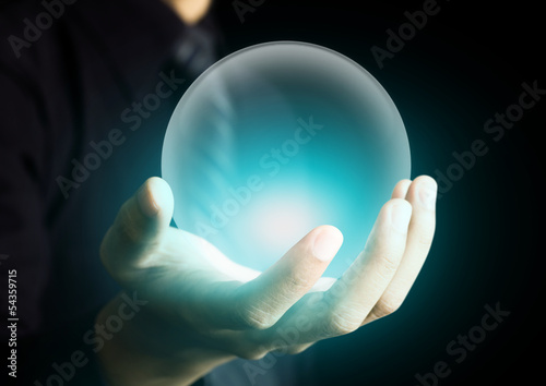 Hand holding a glowing crystal ball
