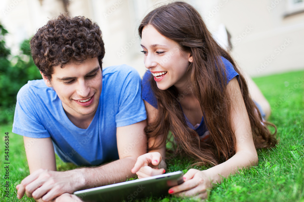 Couple using digital tablet on lawn Couple using digital tablet on lawn