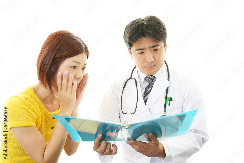 真剣な表情の医師と女性患者 真剣な表情の医師と女性患者