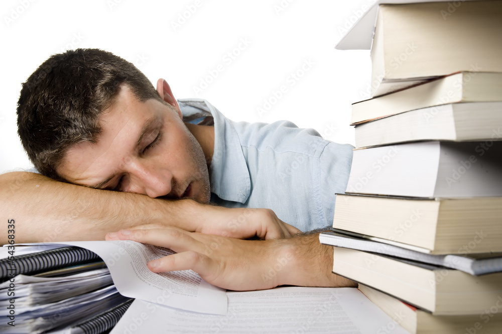 Fototapeta premium Young Man Overwhelmed sleeping over a pile of books