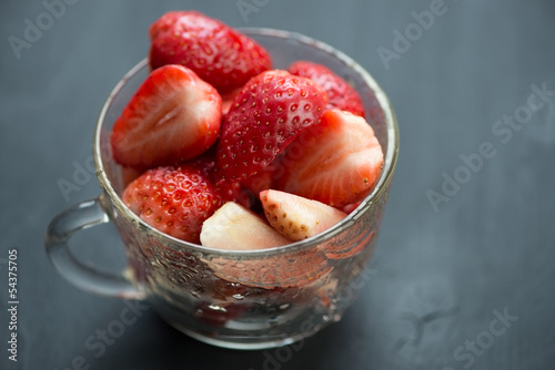 Ripe sliced strawberries in a cup, horizontal shot