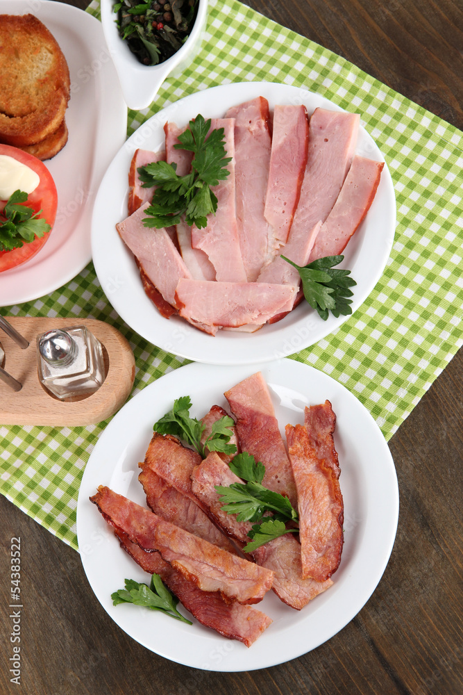 Bacon on plates on napkin on wooden table Bacon on plates on napkin on wooden table