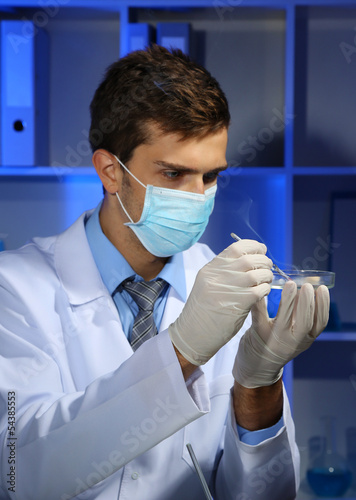 Young laboratory scientist with petri dish working at lab