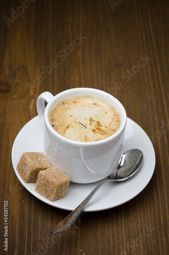 cup of black coffee with foam and cane sugar cubes
