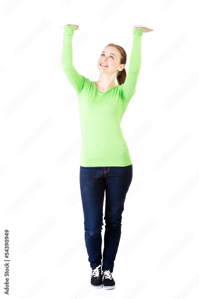 Smiling young woman is holding something abstract above her head Smiling young woman is holding something abstract above her head