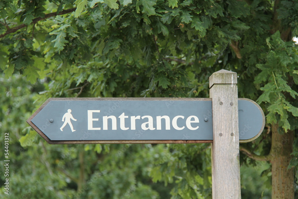 A Sign Post Pointing to a Pedestrian Entrance.