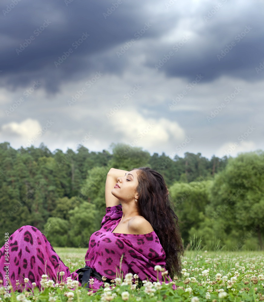 Portrait of young woman sitting on a green lawn Portrait of young woman sitting on a green lawn