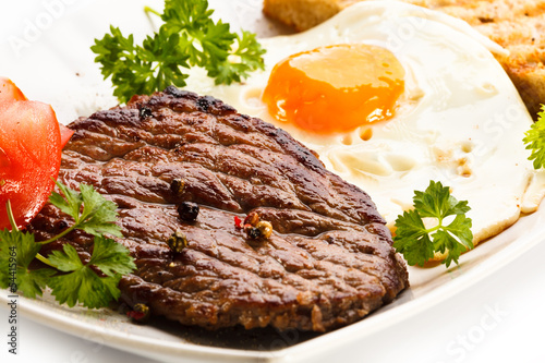 Grilled steak, toast, fried egg and vegetables photo