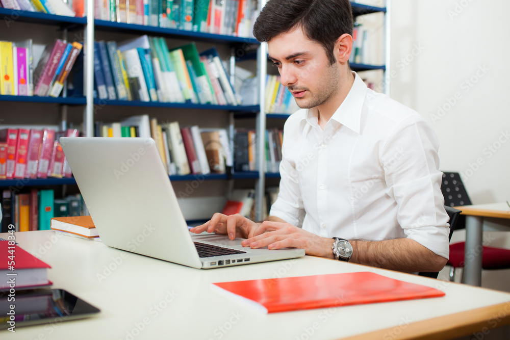 Guy using his laptop in a library Guy using his laptop in a library