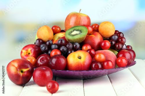 Assortment of juicy fruits on wooden table  on bright