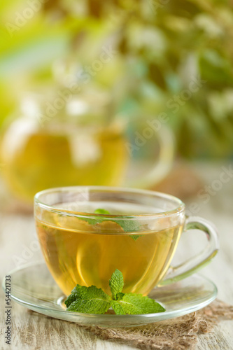 Cup of herbal tea with fresh mint flowers on wooden table