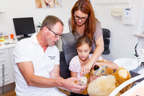 A doctor explains a young kind how they can care the tooth