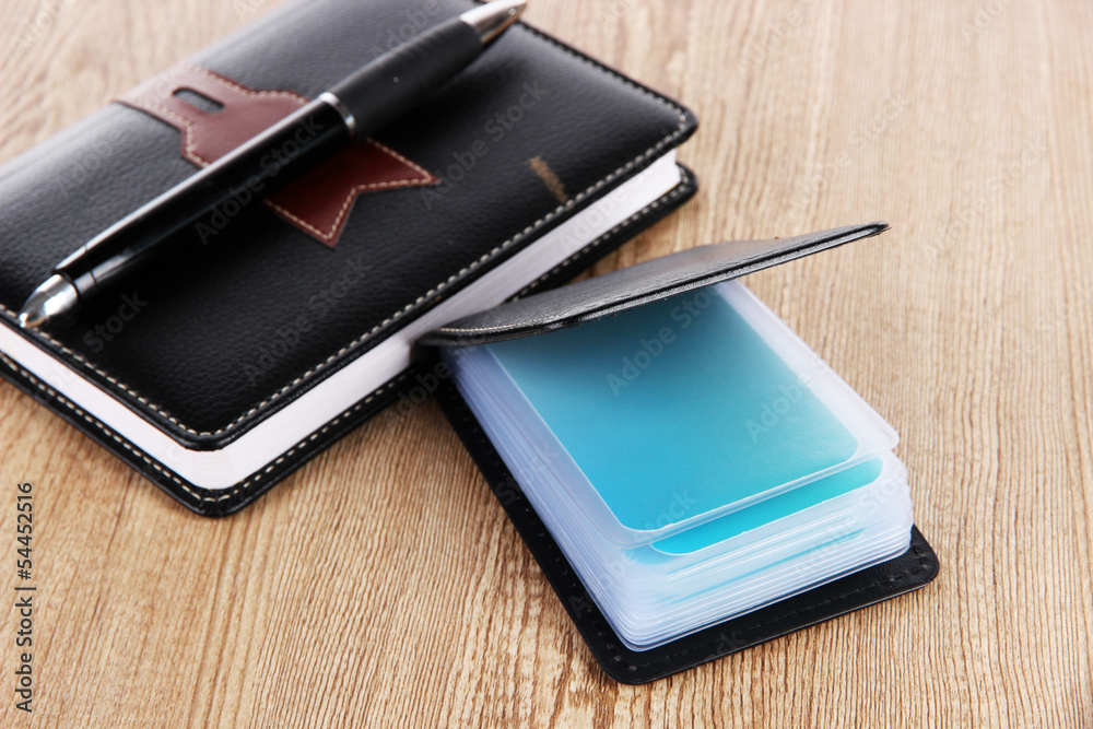 Black business card holder notebook and pen on wooden Black business card holder notebook and pen on wooden