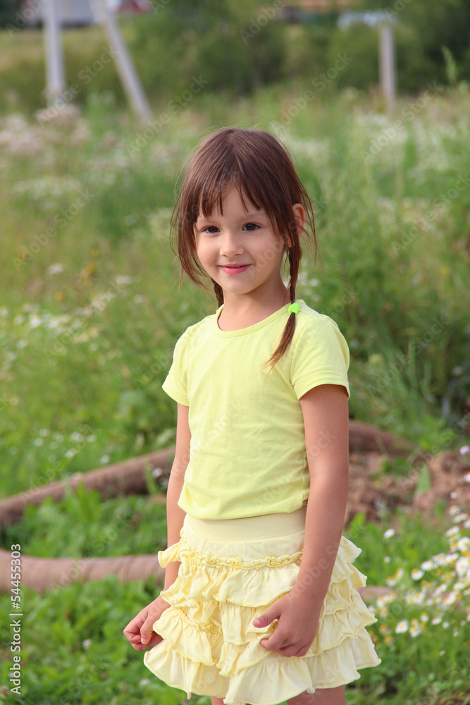 Pretty little girl in yellow skirt smiling outdoors in summer Pretty little girl in yellow skirt smiling outdoors in summer