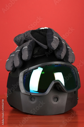 Winter sport glasses, helmet and gloves, on red background