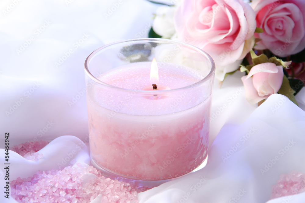 Beautiful candle with flower on white cloth, close up Beautiful candle with flower on white cloth, close up