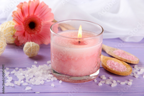 Beautiful pink candle with flower on purple wooden background