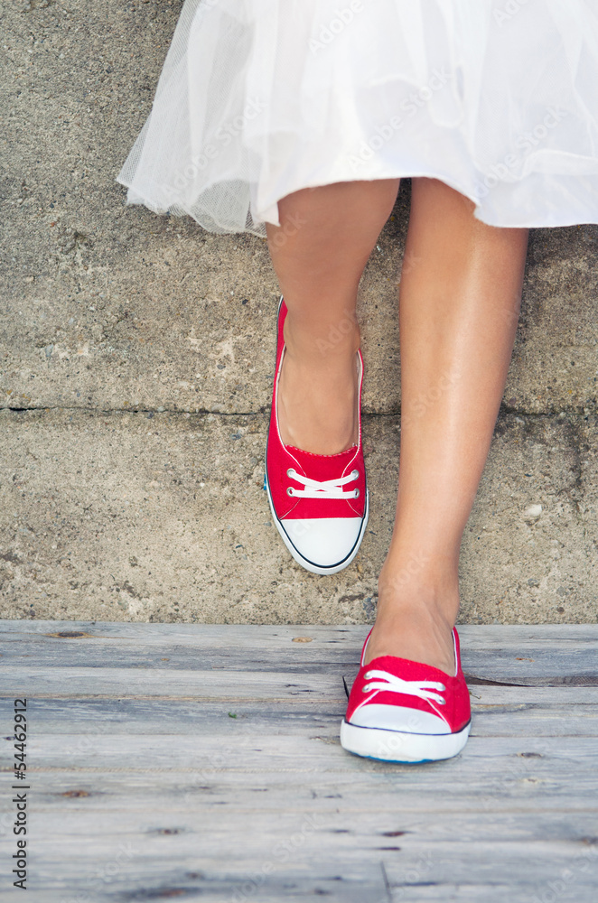 Girl wearing red sneakers leaning on the wall