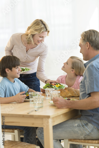 Woman Serving Food To Daughter At Dining Table