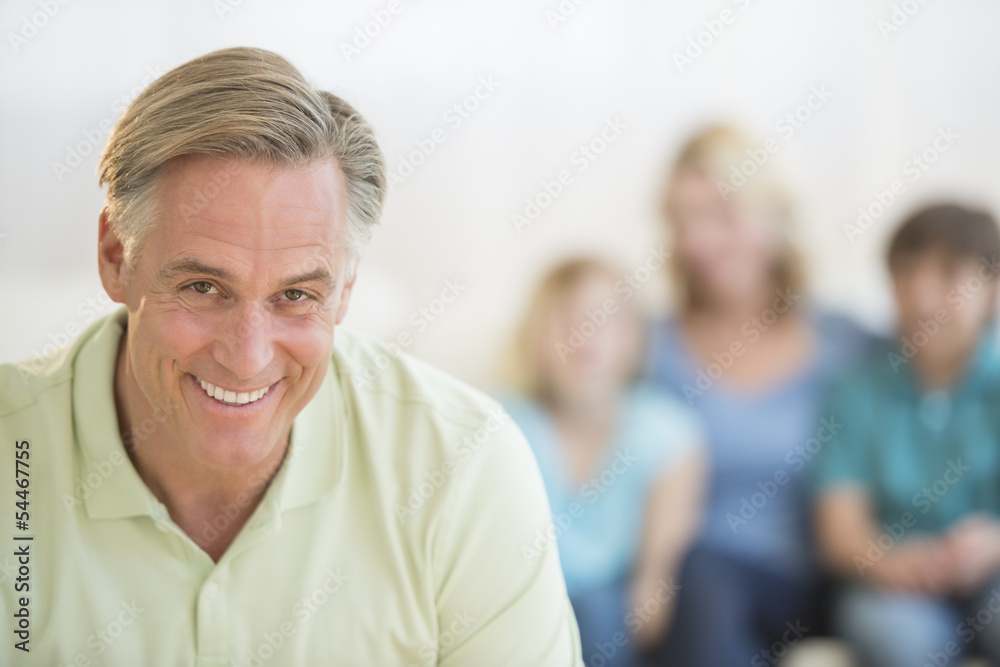 Happy Man With Family Sitting In Background At Home Happy Man With Family Sitting In Background At Home
