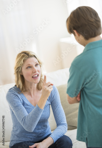 Woman Gesturing While Scolding Son At Home