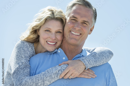 Loving Woman Embracing Man From Behind Against Clear Sky