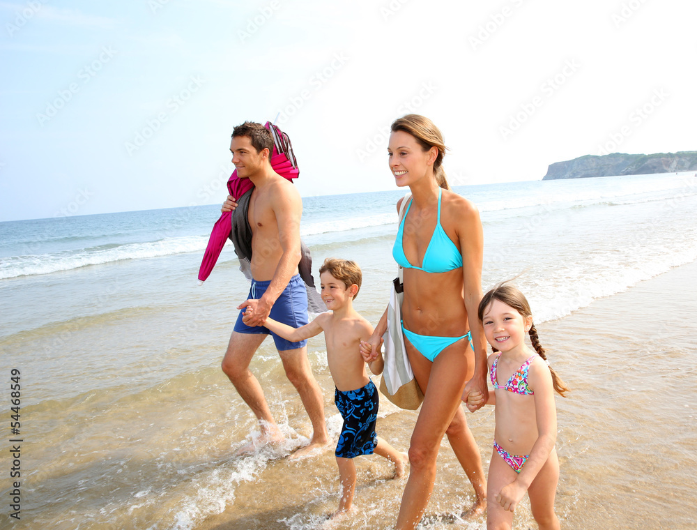 Family in summer vacation walking on the beach