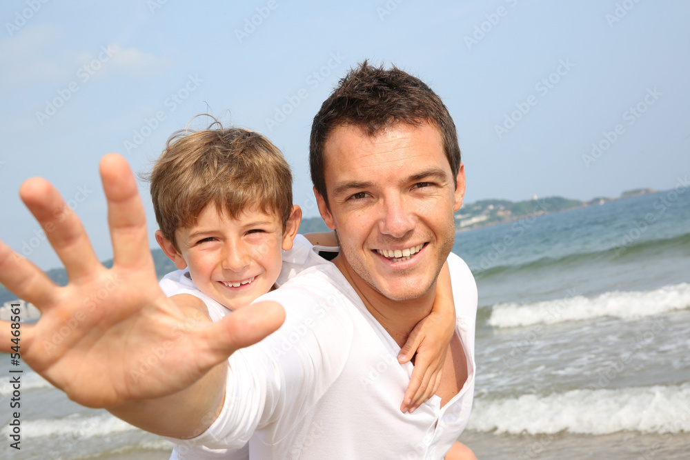 Man holding son on his back at the beach Man holding son on his back at the beach
