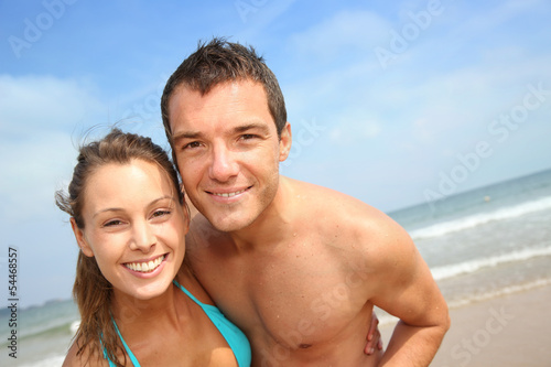 Cheerful young couple standing on the beach © goodluz
