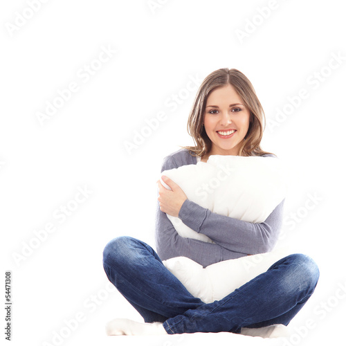 A young brunette woman in jeans holding a white pillow