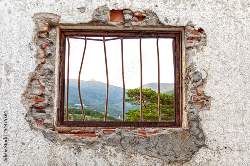 Window red bars on a white wall and demolished with forest view