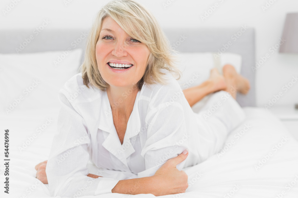 Smiling woman lying on her bed Smiling woman lying on her bed