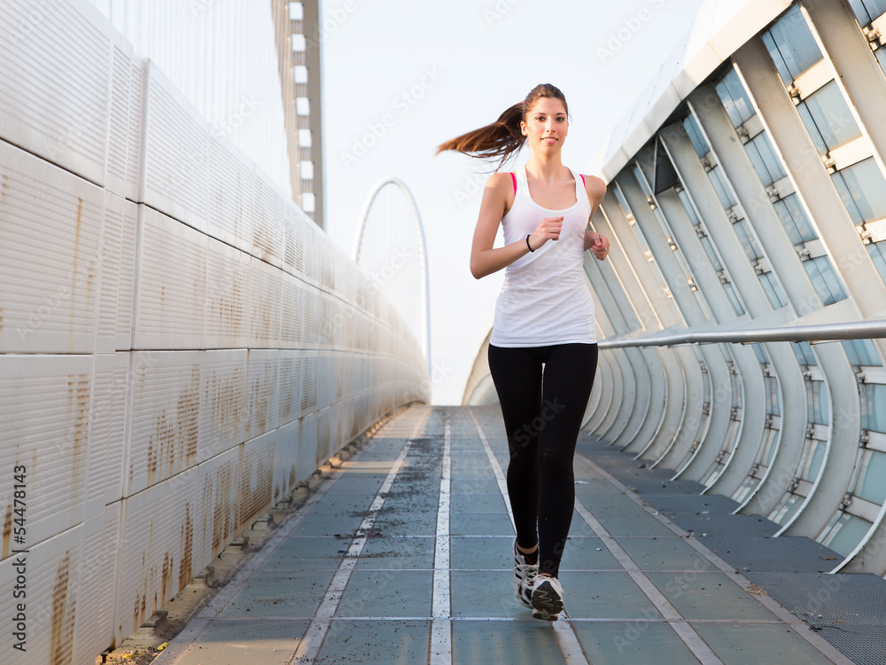 Young woman running outdoors on a modern bridge