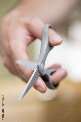 Man s hand with scissors on a background.