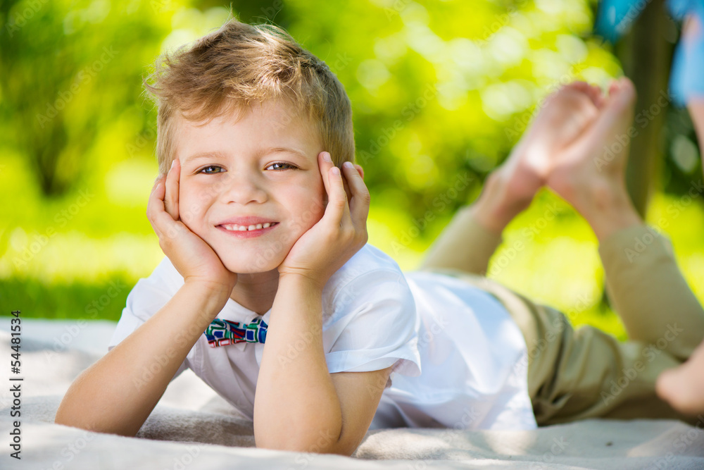 Cute little boy with butterfly lying on green grass Cute little boy with butterfly lying on green grass