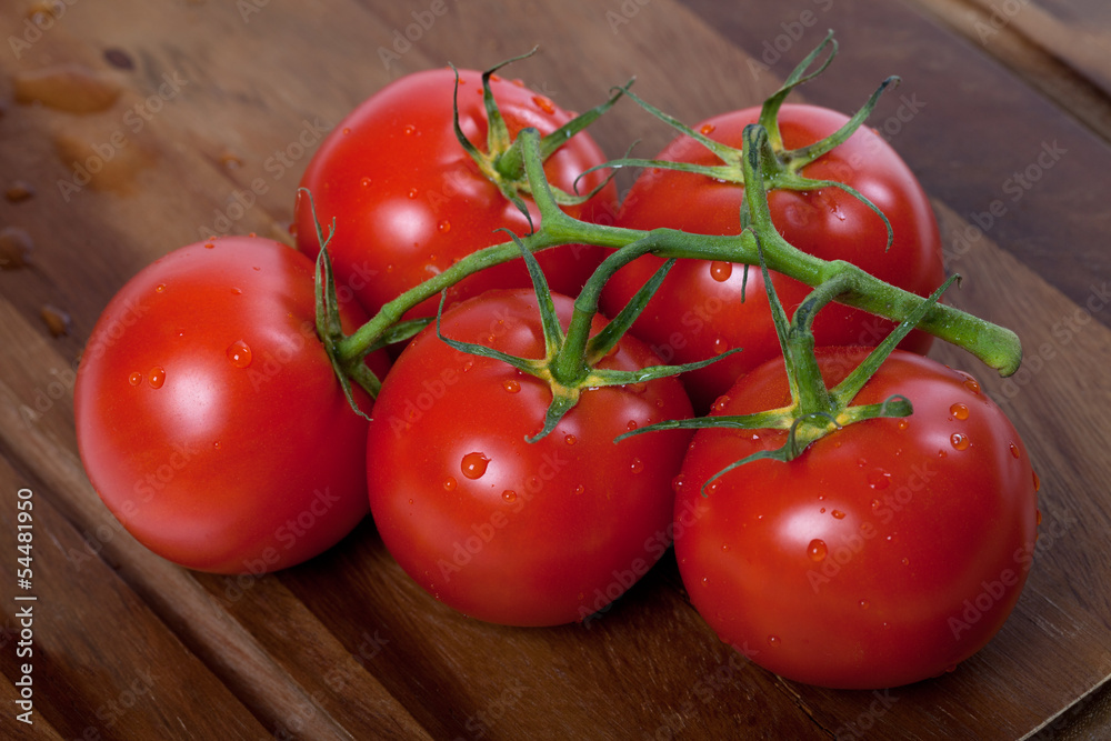 Bunch of fresh tomatoes with water drops on wooden table Bunch of fresh tomatoes with water drops on wooden table