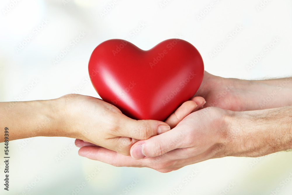 Heart in hands on light background