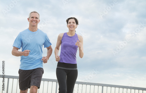 Couple Jogging Against Cloudy Sky