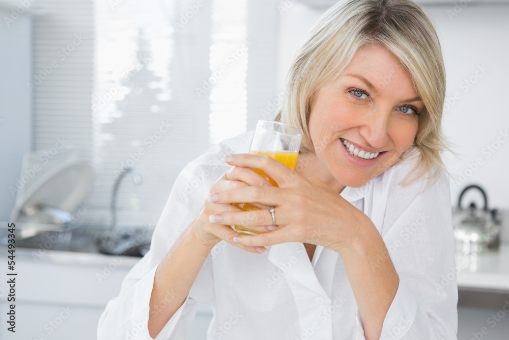 Smiling blonde having orange juice in kitchen Smiling blonde having orange juice in kitchen
