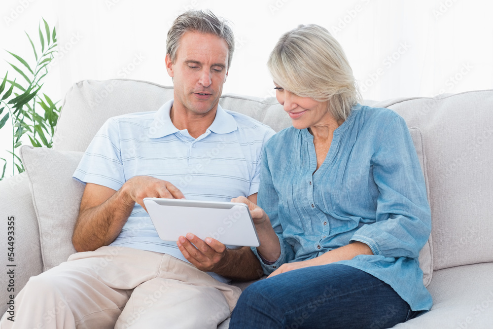 Couple using tablet together on the sofa Couple using tablet together on the sofa