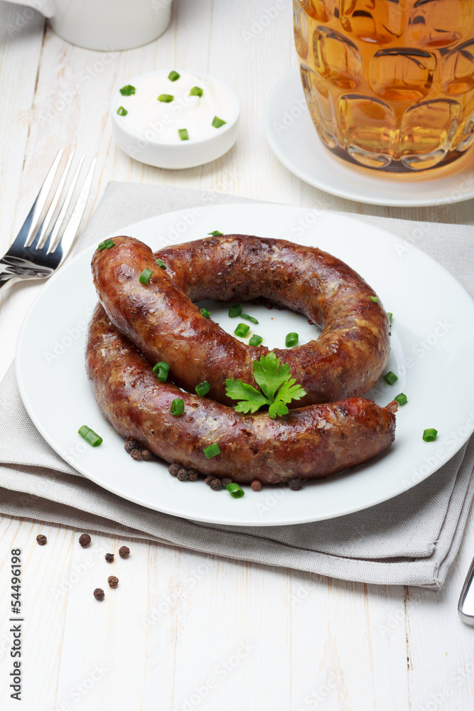 Traditional homemade coiled sausage with beer on wooden table