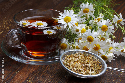 Chamomile tea and dried flowers on wooden table